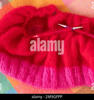 Handgestrickter Pullover aus pinkfarbenem und rotem Mohair-Garn mit Stickerei und Rippnähten, gestrickt auf runden Nadeln. Stockfoto