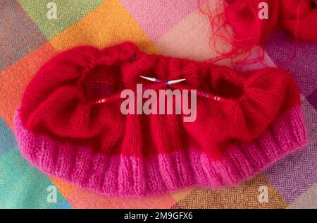 Handgestrickter Pullover aus pinkfarbenem und rotem Mohair-Garn mit Stickerei und Rippnähten, gestrickt auf runden Nadeln. Stockfoto