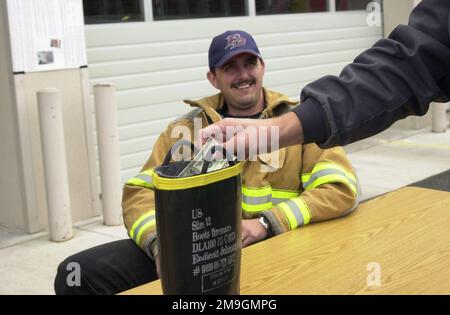 Ein Feuerwehrmann am Kingsley Field Airport sieht zu, wie er Spenden in einen Feuerwehrstiefel wirft. Die Spenden sind für die Familien der Feuerwehrmänner, die beim Zusammenbruch des World Trade Center am 11. September 2001 getötet wurden. Der Einsturz, weil ein Terrorist zwei große Passagierflugzeuge in die Gebäude fliegt, die alle in den Flugzeugen und Tausende im Gebäude töteten. Basis: Kingsley Field State: Oregon (OR) Country: United States of America (USA) Scene Major Command gezeigt: ANG Stockfoto