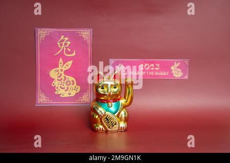 chinesisches Neujahr 2023. Jahr des Hasen mit Maneki Neko, der der Katze Glückskatze winkt Stockfoto