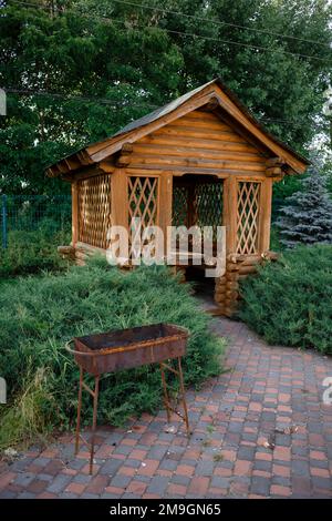 Pavillon für Barbecue oder Hochzeitszeremonie im Waldhintergrund. Holzpavillon am Wasser. Ort für Barbecue oder Hochzeitszeremonie. Hochwertiges Foto Stockfoto