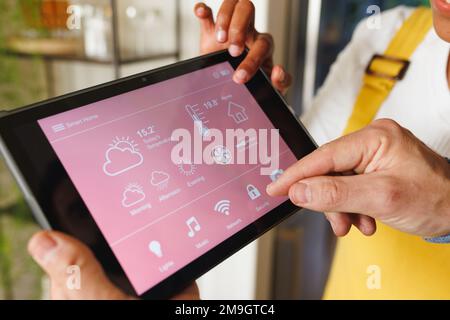 Gekürzte Hände von Paaren, die ein modernes Smart Home über ein digitales Tablet steuern Stockfoto