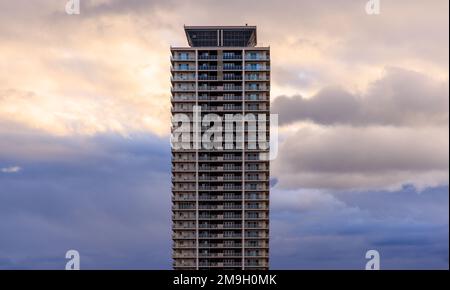 Sonnenuntergang in bewölktem Himmel hinter einem hohen Wohnhaus Stockfoto