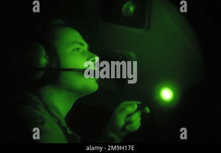 DF-SD-03-17247. [Complete] Scene Caption: Eine Nachtsichtaufnahme, während ein US Air Force C-17A Globemaster III Co-Pilot eine Schalttafel im Cockpit inspiziert, während er unterwegs ist, um das Tri-Wall Aerial Delivery System (TRIADEN) zu liefern, das mit humanitärer Tagesration (HDR) beladen ist. Die Air Force C-17 lieferte humanitäre Tagesrationen (HDR) zur Unterstützung der Operation DAUERHAFTE FREIHEIT von Deutschland an afghanische Flüchtlinge, die sich innerhalb der Grenzen Afghanistans versammelten. Die C-17 trug mehr als 35.000 HDRs, verpackt in 84 TRIADEN-Boxen. Jeder Karton ist 80 Zoll hoch und 48 Zoll quadratisch und enthält 420 HDRs. Die HDRs wir Stockfoto