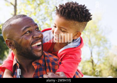 Glücklicher afroamerikanischer Vater und Sohn, die in ihrem Hinterhof lächeln Stockfoto