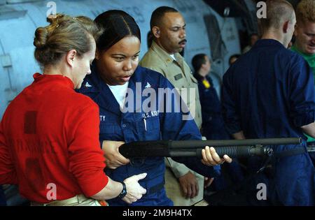 DER LEITER der US-Luftwaffe Kimberly Parkhurst erteilt dem Aviation Storekeeper 3. Class Trisha Charity in der Hangarbucht der USS BATAAN (LHD 5) eine Schrotflintenunterweisung. Die Bataan unterstützt die dauerhafte FREIHEIT der Operation. Betreff Betrieb/Serie: DAUERHAFTE FREIHEITSBASIS: USS Bataan (Linkslenker 5) Stockfoto