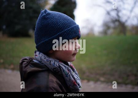 Profil eines Jungen, 9 Jahre alt, im Park, mit Hut und Schal, draußen, Winter - Park des Buttes-Chaumont, 75019, Paris, Frankreich Stockfoto