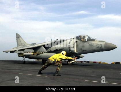 US Navy (USN) CHIEF Aviation Boatswain's Mate (ABC) Steve Guarjardo, ein Aircraft Handling Officer an Bord der USN WASP-KLASSE: Amphibious Assault Ship, USS BATAAN (LHD 5), signalisiert den Start eines US Marine Corps (USMC) AV-8B Harrier-Flugzeugs vom Cockpit. Basis: USS Bataan (Linkslenker-5) Stockfoto
