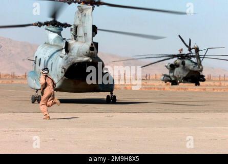 Während DER OPERATION „DAUERHAFTE FREIHEIT“ läuft ein Besatzungschef neben einem CH-46-Hubschrauber mit Helicopter Marine Medium Squadron 365 (verstärkt) in der Nähe des Air Command Element Headquarters am internationalen Flughafen Kandahar, Kandahar, Afghanistan,. Auf der Rampe im Hintergrund befindet sich ein CH-53 Sea Hallion. Betreff Operation/Serie: DAUERHAFTE FREIHEITSBASIS: Internationaler Flughafen Kandahar Land: Szene in Afghanistan (AFG) Hauptkommando gezeigt: 26. MEU (SOC) Stockfoto