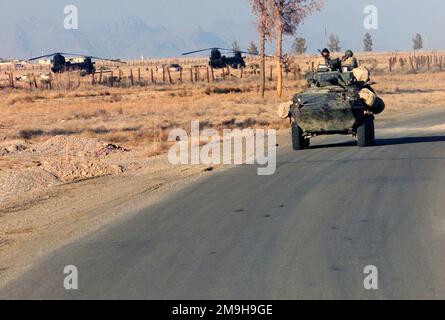 Marines mit Alpha Company, Zweiter Aufklärungsbataillon der leichten Panzerung, 26. Marineexpeditionseinheit (geeignet für Sondereinsätze) fahren ihr LAV-25 (Leichtgepanzertes Fahrzeug-25) während DER OPERATION DAUERHAFTE FREIHEIT zum US-bemannten Tor am Internationalen Flughafen Kandahar, Kandahar, Afghanistan. Im Hintergrund auf der Parkrampe des Luftwaffenstützpunkts befinden sich zwei Army CH-47 Chinooks. Betreff Operation/Serie: DAUERHAFTE FREIHEITSBASIS: Internationaler Flughafen Kandahar Land: Afghanistan (AFG) Stockfoto