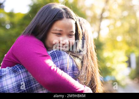 Glückliche asiatische Mutter und Tochter, die sich im Garten umarmen Stockfoto