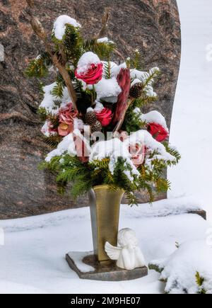 Schneebedeckte Blumenarrangements auf dem Friedhof Stockfoto