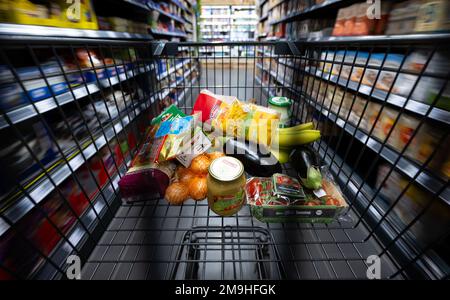 Neubiberg, Deutschland. 18. Januar 2023. Verschiedene Lebensmittel liegen in einem Einkaufswagen in einem Supermarkt. Angesichts der hohen Inflation erwarten die Verbraucherverbände einen weiteren Anstieg der Lebensmittelpreise. Kredit: Sven Hoppe/dpa/Alamy Live News Stockfoto