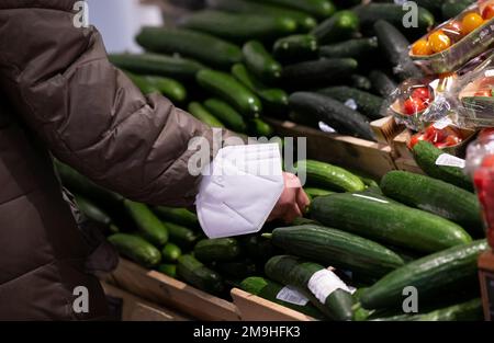 Neubiberg, Deutschland. 18. Januar 2023. Eine Frau steht bei einer Ausstellung von Gurken im Obst- und Gemüsesegment eines Supermarkts. Angesichts der hohen Inflation erwarten die Verbraucherverbände einen weiteren Anstieg der Lebensmittelpreise. Kredit: Sven Hoppe/dpa/Alamy Live News Stockfoto