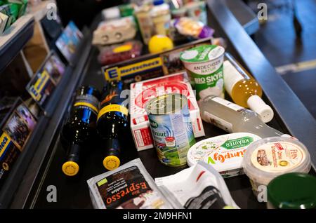 Neubiberg, Deutschland. 18. Januar 2023. Lebensmittel liegen auf dem Förderband an der Kasse in einem Supermarkt. Angesichts der hohen Inflation erwarten die Verbraucherverbände einen weiteren Anstieg der Lebensmittelpreise. Kredit: Sven Hoppe/dpa/Alamy Live News Stockfoto