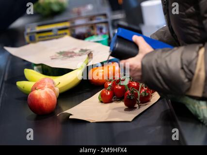 Neubiberg, Deutschland. 18. Januar 2023. Lebensmittel liegen auf dem Förderband an der Kasse in einem Supermarkt. Angesichts der hohen Inflation erwarten die Verbraucherverbände einen weiteren Anstieg der Lebensmittelpreise. Kredit: Sven Hoppe/dpa/Alamy Live News Stockfoto