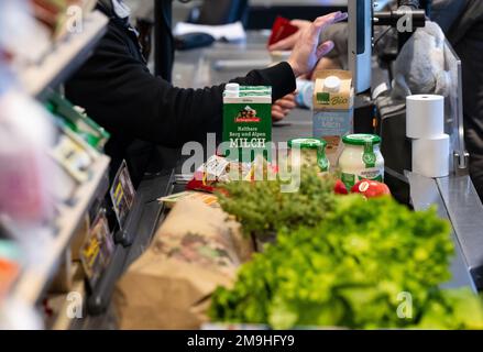 Neubiberg, Deutschland. 18. Januar 2023. Lebensmittel liegen auf dem Förderband an der Kasse in einem Supermarkt. Angesichts der hohen Inflation erwarten die Verbraucherverbände einen weiteren Anstieg der Lebensmittelpreise. Kredit: Sven Hoppe/dpa/Alamy Live News Stockfoto