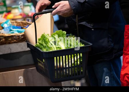 Neubiberg, Deutschland. 18. Januar 2023. Ein Mann steht an der Kasse mit einem Warenkorb in einem Supermarkt. Angesichts der hohen Inflation erwarten die Verbraucherverbände einen weiteren Anstieg der Lebensmittelpreise. Kredit: Sven Hoppe/dpa/Alamy Live News Stockfoto