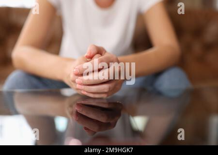 Frau mit verbundenen Händen, die auf der Couch sitzt. Stockfoto