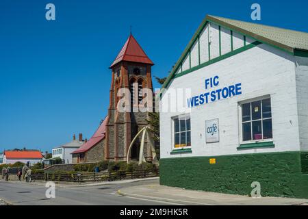 Straßenszene mit dem FIC West Store und Christ Church Cathedral mit einem Wal-Knochenbogen, auf der Ross Road in Port Stanley, Falkland Islands. Stockfoto