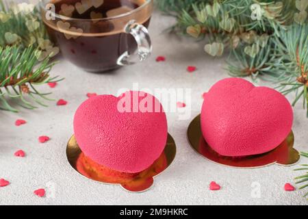 Leuchtende Mousse Cakes Herzen mit pinkfarbenem Velor Beschichtung und eine Tasse Kaffee zum Valentinstag Stockfoto