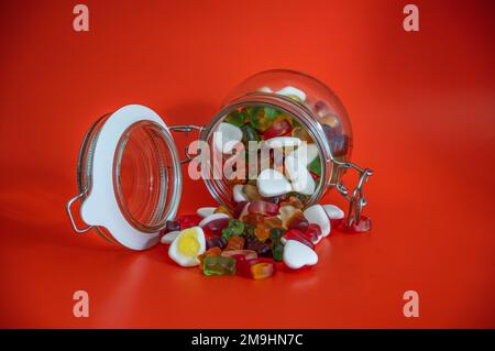 Süßigkeiten-Becher geöffnet mit Süßigkeiten auf rotem Tisch isoliert Stockfoto