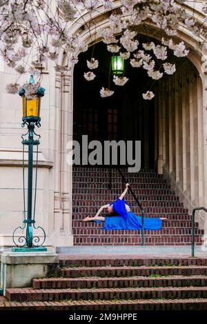 Akrobat in blauem Kleid, der sich auf der Treppe erstreckt, University of Washington, Seattle, Washington State, USA Stockfoto