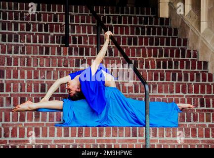 Akrobat in blauem Kleid, der sich auf der Treppe erstreckt, University of Washington, Seattle, Washington State, USA Stockfoto