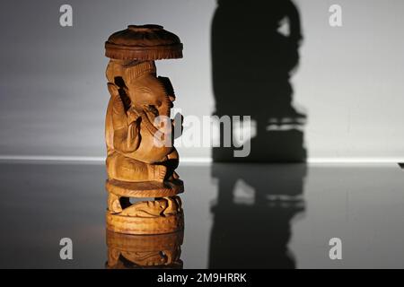 Traditionelles indisches hölzernes Souvenir. Gott, Ganesha. Foto im Dunkeln im Strahl einer Laterne. Stockfoto