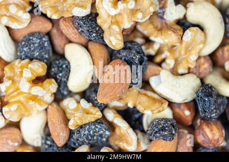 Mit Haselnüssen, Cashews und Rosinen gestapelte Nüsse in einem Makrofoto. Stockfoto