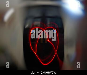 Eine helle Herzform gegen verschwommene dunkle Holztüren, wie sie in öffentlichen Einrichtungen zu finden sind Stockfoto