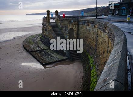 Meereswand mit Stufen hinunter zum ursprünglichen kostenlosen Wasserhahn oder Spaw im Scarborough Spa Stockfoto