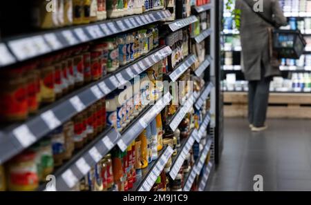 Neubiberg, Deutschland. 18. Januar 2023. Eine Frau steht in einem Supermarkt mit einem Warenkorb. Kredit: Sven Hoppe/dpa/Alamy Live News Stockfoto