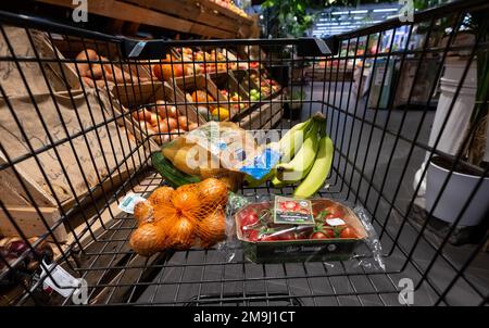 Neubiberg, Deutschland. 18. Januar 2023. Verschiedene Lebensmittel liegen in einem Einkaufswagen in einem Supermarkt. Kredit: Sven Hoppe/dpa/Alamy Live News Stockfoto