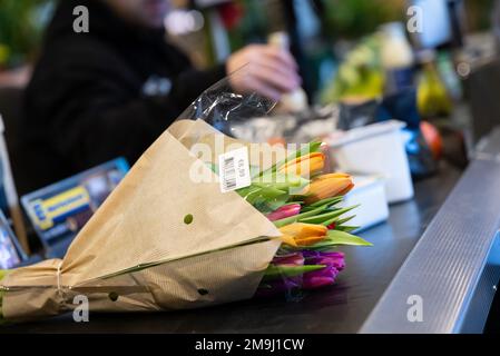 Neubiberg, Deutschland. 18. Januar 2023. Schnittblumen liegen auf dem Förderband an der Kasse in einem Supermarkt. Kredit: Sven Hoppe/dpa/Alamy Live News Stockfoto