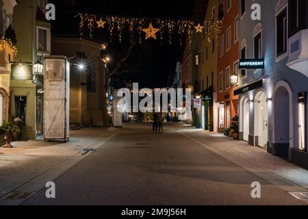 KITZBÜHEL, ÖSTERREICH - 07. JANUAR 2023: Nachtsicht auf Kitzbühel, eine kleine Alpenstadt. Gehobene Geschäfte und Cafés säumen die Straßen des mittelalterlichen Zentrums. Stockfoto