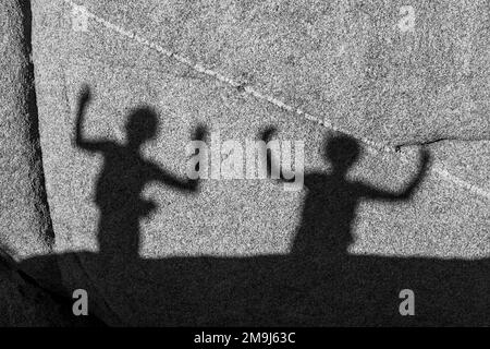 Kinder spielen mit Schatten auf einem Felsen im Juschua Tree Nationalpark Stockfoto