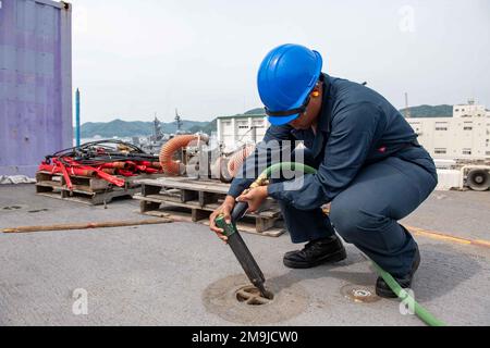 SASEBO, Japan (19. Mai 2022) Aviation Boatswain’s Mate (Handling) Airman Recruit Jynae Gilyard, aus Greensboro, N.C., dem nach vorn ausgesetzten Amphibienschiff USS America (LHA 6) zugewiesen, splittert Farbe von einer Gleitöse auf dem Cockpit des Schiffes. Amerika, das führende Schiff der America Amphibious Ready Group, ist im Zuständigkeitsbereich der US-amerikanischen 7.-Flotte tätig, um die Interoperabilität mit Verbündeten und Partnern zu verbessern und als bereitstehende Eingreiftruppe zur Verteidigung von Frieden und Stabilität in der Region Indo-Pazifik zu dienen. Stockfoto