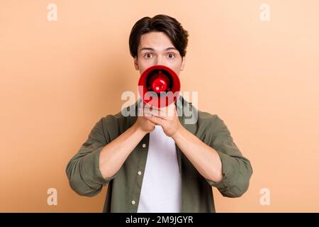 Foto eines lustigen Schülers, der schreit Lautsprecher-Ankündigung Nachrichten Megafon Informationen tragen Khaki-Hemd isoliert auf beigefarbenem Hintergrund Stockfoto