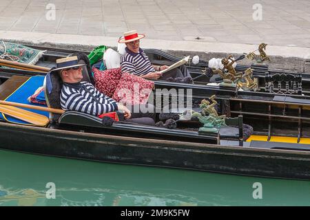 Zwei Gondoliere ruhen in ihren Gondeln, die Seite an Seite in Venedig, Italien, geparkt sind. Stockfoto