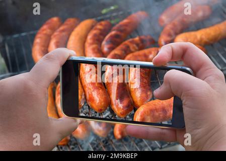 Essensfotografie von gebackenen Würstchen, Fleisch. Foto von gebackenem Fleisch, Kebabs mit Smartphone schrubben. Stockfoto