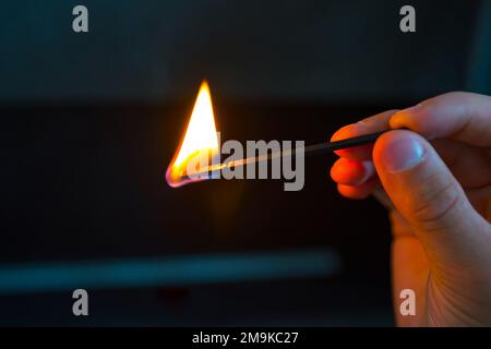 Hand mit brennendem Streichholz auf Schwarz Stockfoto