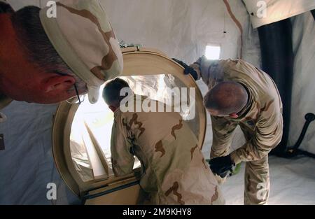 US Navy (USN) Hospital Corpsman Second Class (HM2) Johnathan Bradford (Zentrum) und USN HM2 Thomas Miller (rechts), beide der 2. Force Services Support Group (FSSG) zugeteilt, arbeiten zusammen, um eine Patientenschleuse für ein chemisch-biologisches Schutzdach (CBPS) zu montieren, während DAS US Department of Defense (DOD) Equipment SPECIALIST, Herr Dan Breitenstein leitet eine Übung im Camp Coyote, Kuwait, während der Operation DAUERHAFTE FREIHEIT. Die CBPS ist ein hochmobiles chemisch geschütztes Schutzsystem für den medizinischen Notfalleinsatz in vorderen Schlachtgebieten. Betreff Operat Stockfoto