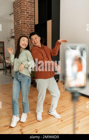 Asiatische Einflussnehmer nehmen Videos auf Smartphone auf, tanzen mit der Kamera, Lifestyle-Vlogger machen Inhalte für Blog Stockfoto