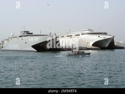 030225-N-1050K-001. [Complete] Scene Caption: Sealift-Fahrzeuge der US Navy (USN) und der US Army (USA) sitzen zusammen auf der Pier-Seite unter den wachsamen Augen der US-amerikanischen und kuwaitischen Hafenpatrouille. Die Navy Joint Venture (HSV-X1) (links) und die Army's Spearhead (TSV-1x) sind Hochgeschwindigkeitskatamarane, die von WERFTEN VON INCAT Australia entworfen und gebaut wurden. Der Entwurf des gemeinsam genutzten Schiffs wurde vom Navys Warfare Development Command in enger Partnerschaft mit Elementen der USA, der USN, des US Marine Corps (USMC) und der US Coast Guard (USCG) koordiniert. Die Schiffe sind beeindruckend schnell und können Truppen bewegen und ausrüsten Stockfoto