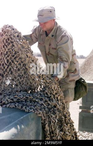 US Marine (USMC) Corporal (CPL) James M. Ramsey, 1. Bataillon, 4. Marines, Headquarters & Service (H&S) Company, wendet cammie (Camouflage)-Netze über Munitionskästen an, während sie im Living Support Area 1 (LSA 1) Munition überwachte, um die Operation DAUERHAFTE FREIHEIT zu unterstützen. Land: Kuwait (KWT) Stockfoto