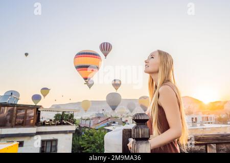 Eine Touristin, die Heißluftballons in Kappadokien, Türkei, ansieht. Happy Travel in Turkey Concept. Eine Frau auf einem Berggipfel, die eine wunderbare Aussicht genießt Stockfoto