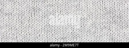 Gestrickter grauer Hintergrund. Großer Strickstoff mit Muster. Nahaufnahme einer Strickdecke. Horizontale Verzierung. Banner Stockfoto