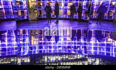 London, Großbritannien. 18. Januar 2023. Menschen und Gebäude spiegeln sich in der Installation wider. Emergence by This is Loop befindet sich am Montgomery Square und ist eine große Skulptur, die aus einem mehrfarbigen zweifarbigen Spiegel und beweglichem Licht besteht. Das jährliche Winter Lights Festival beginnt heute mit 22 Lichtinstallationen und beeindruckenden Kunstausstellungen rund um Canary Wharf in London. Das öffentliche Festival läuft bis zum 28. Januar und kann kostenlos besucht werden. Kredit: Imageplotter/Alamy Live News Stockfoto