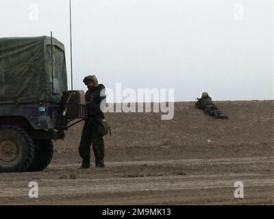 MARINES des US Marine Corps (USMC) von Headquarters (HQTRS) Company, Regimental Combat Team 5. Marines (RCT-5), 1. Marine Division (MARDIV), Camp Pendleton, Kalifornien (CA), bieten Sicherheit mit 5,56 mm M16A2 Sturmgewehren, An einem ungeplanten Halt für ihren Konvoi von Mehrzweckfahrzeugen mit hoher Mobilität (HMMWV) auf dem Weg zum taktischen Versammlungsgebiet (TAA) während der Operation „IRAQI FREEDOM“. (Unterdurchschnittliches Bild). Betreff Operation/Serie: IRAQI FREEDOM Country: Iraq (IRQ) Stockfoto